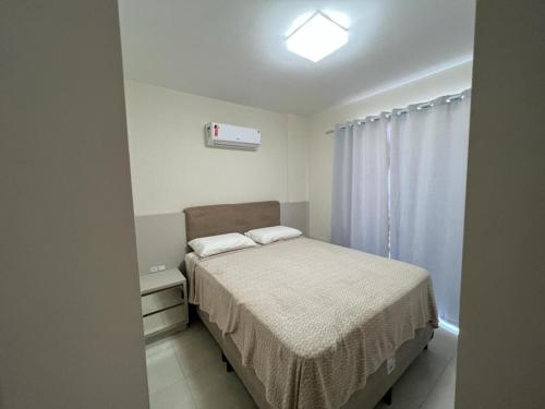 Habitación pequeña con cama y ventana en Apartamento Novo Praia de Bombas en Bombinhas