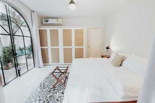 a white bedroom with a bed and a large window at Casa La Sultana Amazing restored house with pool in Valladolid