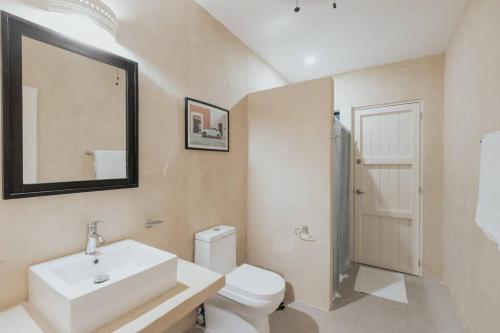 uma casa de banho com um lavatório, um WC e um espelho. em Casa La Sultana: Amazing new house with pool em Valladolid