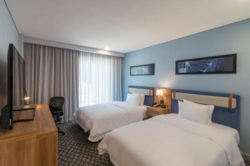 a hotel room with two beds and a flat screen tv at Hampton by Hilton Aguascalientes Downtown in Aguascalientes