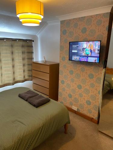 1 dormitorio con 1 cama y TV en la pared en Lovely 3 bed house with patio/bbq, en Slades Green