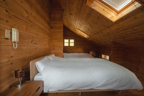 a bedroom with a white bed in a wooden cabin at The Lodge 弟子屈 in Teshikaga