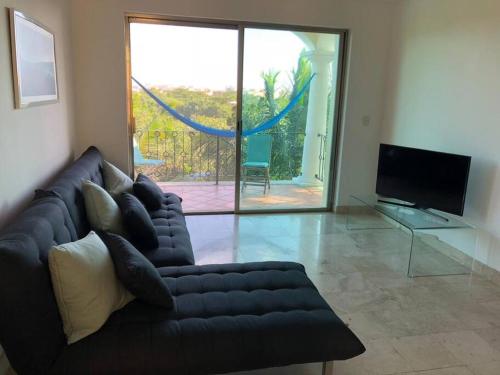 a living room with a black couch and a sliding glass door at Villa Talia, Relax, beach & Nature in Puerto Aventuras