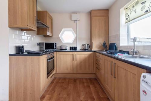 a large kitchen with wooden cabinets and a sink at Your Nottingham Haven - 3 Bed House with Free Wifi and Parking in Nottingham