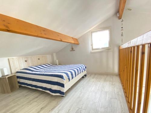 een slaapkamer met een bed met een blauw en wit gestreepte deken bij Maison Bretignolles-sur-Mer, 2 pièces, 4 personnes - FR-1-231-267 in Brétignolles-sur-Mer