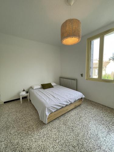 a white bedroom with a bed and a window at Chambre au calme en cœur de ville in Cavaillon