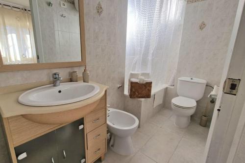 y baño con lavabo, aseo y espejo. en Apartamento de playa en paseo marítimo en Benicàssim