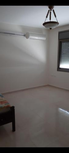Salah Khamlan Apartments في نابلس: غرفة بيضاء مع مروحة ونافذة