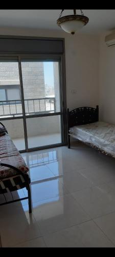 a room with two beds and a large window at Salah Khamlan Apartments in Nablus