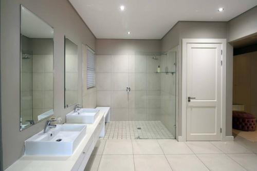 a bathroom with two sinks and a walk in shower at Luxury Zimbali Villa*7 Grandview*Seaview*Pool* in Ballito