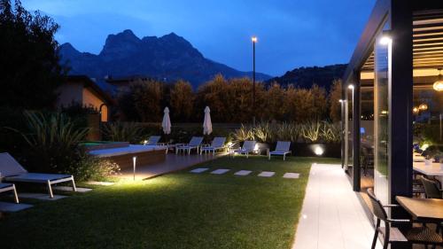 a patio with chairs and a lawn with mountains in the background at Hotel Villa Alberta in Nago-Torbole
