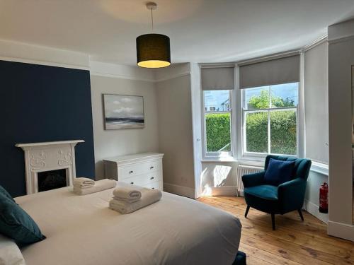 a bedroom with a bed and a chair and windows at Home in Dartmouth, Devon with Private Parking in Dartmouth