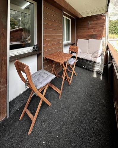 a porch with two chairs and a table and a bench at Chalet Ribi in Grindelwald