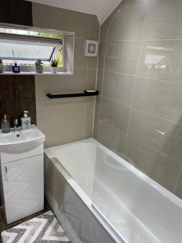 a bathroom with a tub and a sink at Lovely 3 bed house with patio/bbq in Slades Green