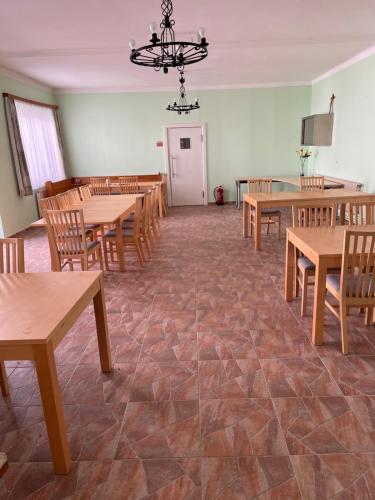 a dining room with wooden tables and chairs and a chandelier at Beherbergungsbetrieb Madle in Deutsch Altenburg