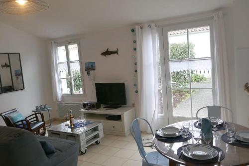 un salon avec une table et une télévision dans l'établissement Maison PASSIFLORE, à Saint-Denis-dʼOléron