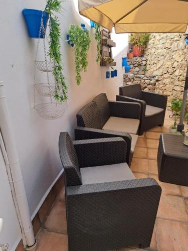a patio with chairs and an umbrella and plants at La Gonzala in Zahara de la Sierra