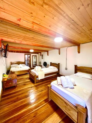 a room with three beds and a wooden ceiling at Hotel Campestre la Playa in Betania