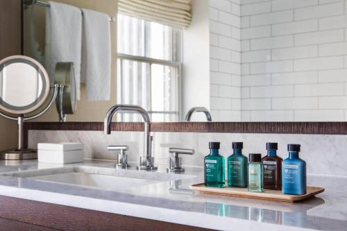 a bathroom sink with three bottles of soap on a counter at The Mayflower Hotel, Autograph Collection in Washington, D.C.