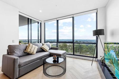 a living room with a couch and large windows at Exquisite High-End Retreat in Macquarie Park in Sydney