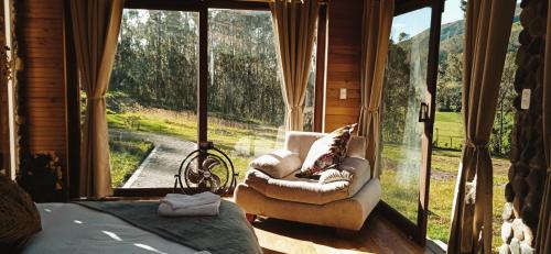 a bedroom with a bed and a chair in front of a window at The Cottage Angochagua in Ibarra