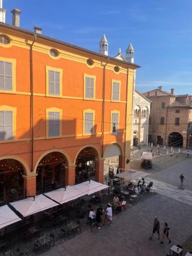 duży pomarańczowy budynek z ludźmi siedzącymi poza nim w obiekcie Duomo 12 w mieście Modena