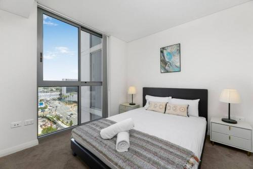 a bedroom with a large bed and a large window at Spacious 2 beds Apt near Airport in Sydney