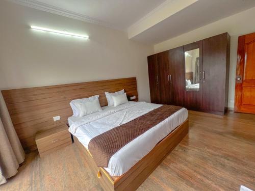 a bedroom with a large bed with a wooden headboard at Hotel Elite by Agira- Spacious Apartments with Balcony in Yelahanka