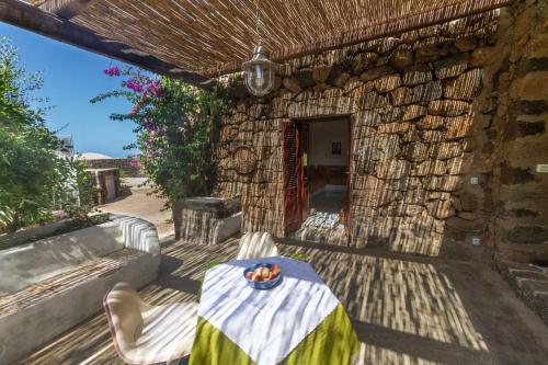 a table and chairs in front of a stone building at Dammuso i Pini di Kaddiuggia (CIR19081014C224053) & Dammuso di Mena (CIR 19081014C224052 in Pantelleria