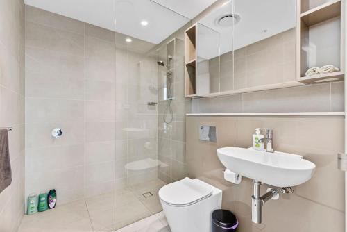La salle de bains est pourvue de toilettes blanches et d'un lavabo. dans l'établissement Luxury 2BR APT in heart of Macquarie Park, à Sydney