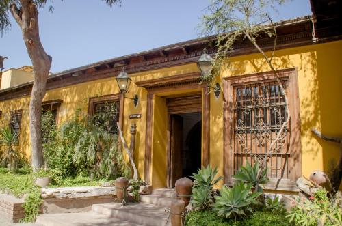 a yellow house with a door and a tree at Hotel & Hacienda El Carmelo in Ica