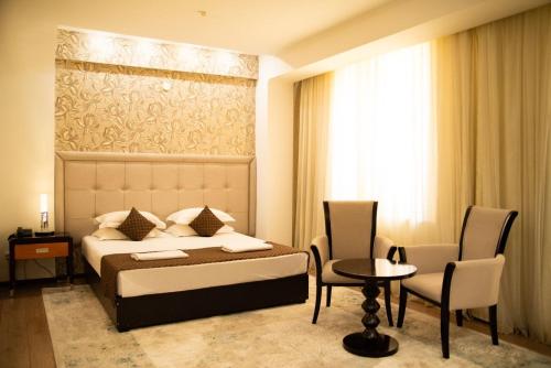 a hotel room with a bed and a table and chairs at Hotel Zhibek Zholy in Shymkent