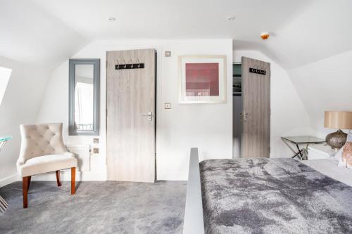 a bedroom with two doors and a chair and a bed at The Secret, Stylish & Spacious En Suite in Blandford Forum, Dorset in Blandford Forum