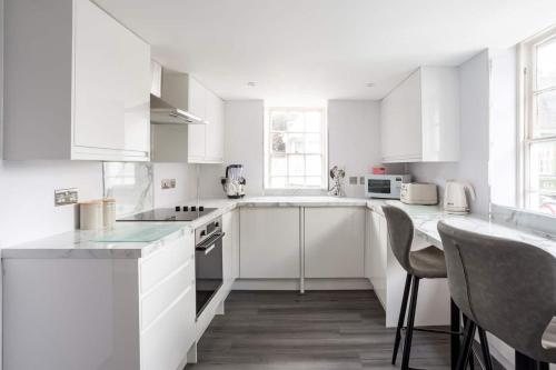 a white kitchen with white cabinets and chairs at The Secret, Stylish & Spacious En Suite in Blandford Forum, Dorset in Blandford Forum