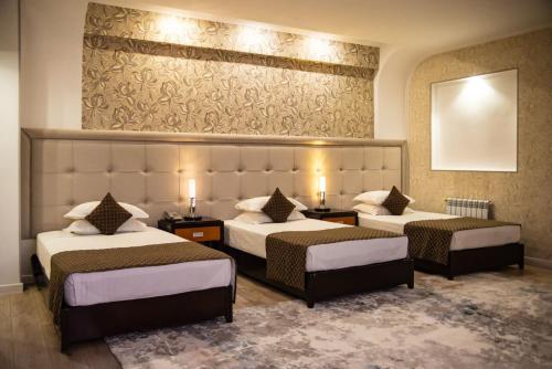 a hotel room with two beds and a mirror at Hotel Zhibek Zholy in Shymkent