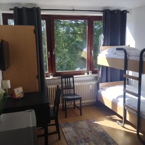 ハンブルクにあるMonteurzimmer in Hamburg West bei Hansezimmerのベッドルーム1室(二段ベッド1組、デスク、窓付)が備わります。