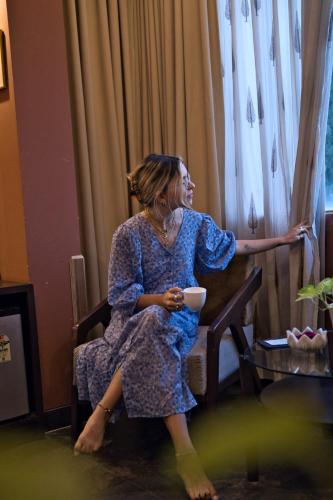 a woman sitting in a chair looking out a window at Ekaa Villa near Taj Mahal in Agra