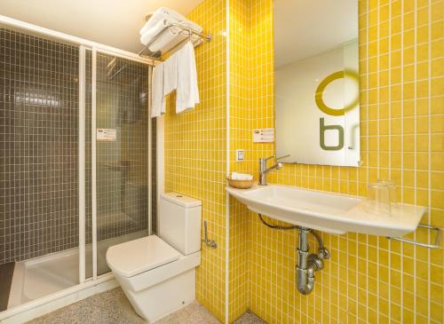 Baño de azulejos amarillos con lavabo y aseo en Apartamentos Mix Bahia Real en El Arenal