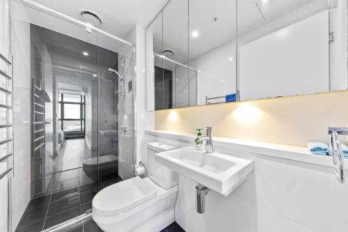 Baño blanco con aseo y lavamanos en Lovely 2 bedroom APT in centre of Sydney Olympic Park en Sídney