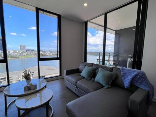 a living room with a couch and a table and windows at Your Luxury Weekend Getaway in Wentworth Point in Sydney