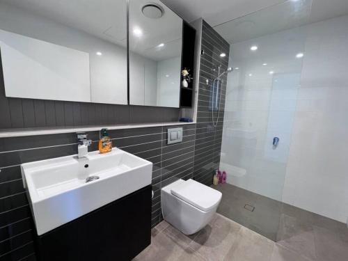 a bathroom with a sink and a toilet and a mirror at Your Luxury Weekend Getaway in Wentworth Point in Sydney