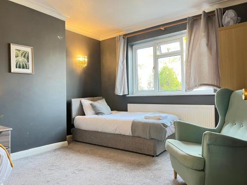 ein Schlafzimmer mit einem Bett, einem Fenster und einem Stuhl in der Unterkunft Airport Garden Rooms in Feltham