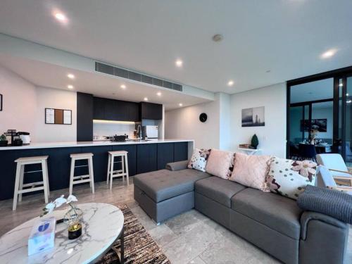 a living room with a couch and a kitchen at High Level Fabulous View 4Beds APT in Olympic Park in Sydney