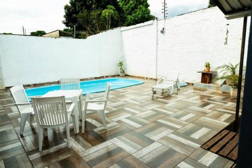 une terrasse avec une table, des chaises et une piscine dans l'établissement Casa na Fronteira, à Foz do Iguaçu