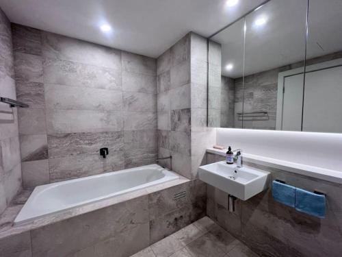 Un baño con bañera blanca y lavabo. en High Level Fabulous View 4Beds APT in Olympic Park, en Sídney