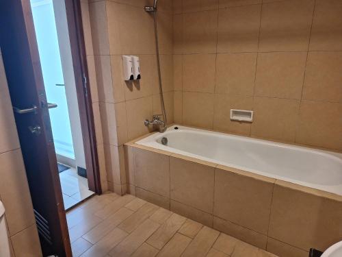 a bathroom with a bath tub and a toilet at Javein Griyadi Hotel in Jakarta