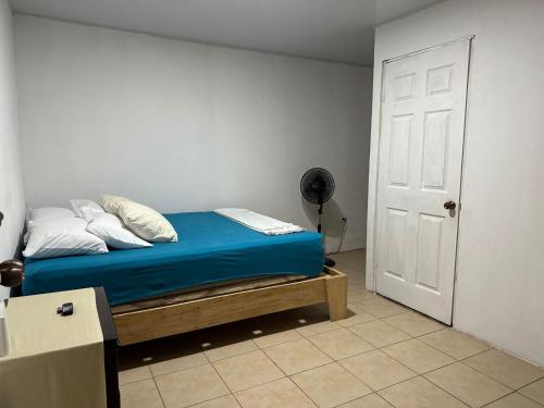 a bedroom with a bed with blue sheets and white pillows at Puente Real Hostel in Liberia