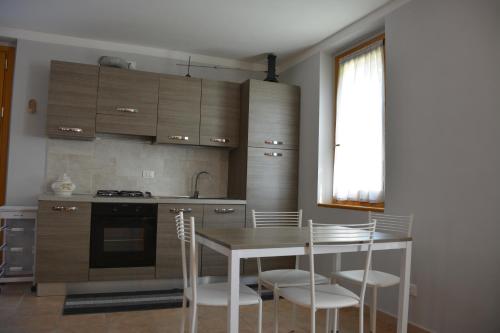 een keuken met een tafel en stoelen en een fornuis bij BAITA BELLAVISTA Affiliato Best-Incoming in Adrara San Rocco