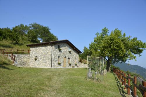 een oud stenen gebouw in een veld met een hek bij BAITA BELLAVISTA Affiliato Best-Incoming in Adrara San Rocco