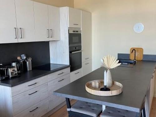 une cuisine avec des armoires blanches et un comptoir noir dans l'établissement Appartement en front de mer à Villers-sur-Mer face au Casino, 2P tout équipé avec parking privatif - FR-1-712-14, à Villers-sur-Mer